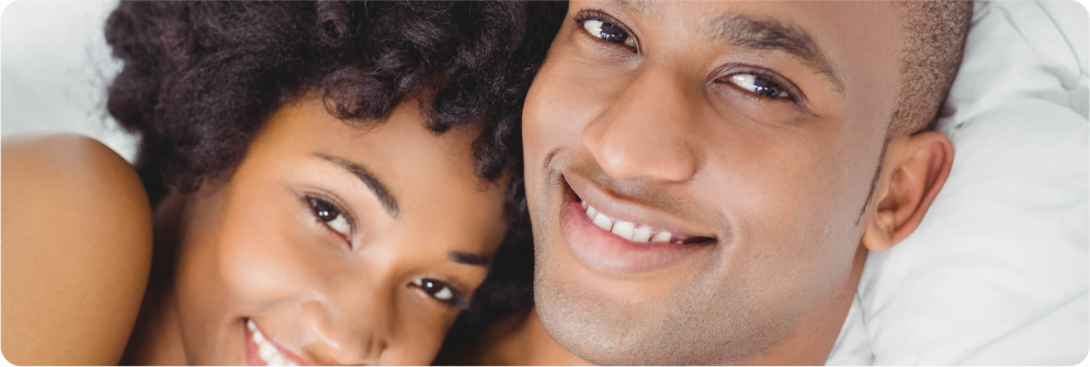 man and women lying on bed and smiling